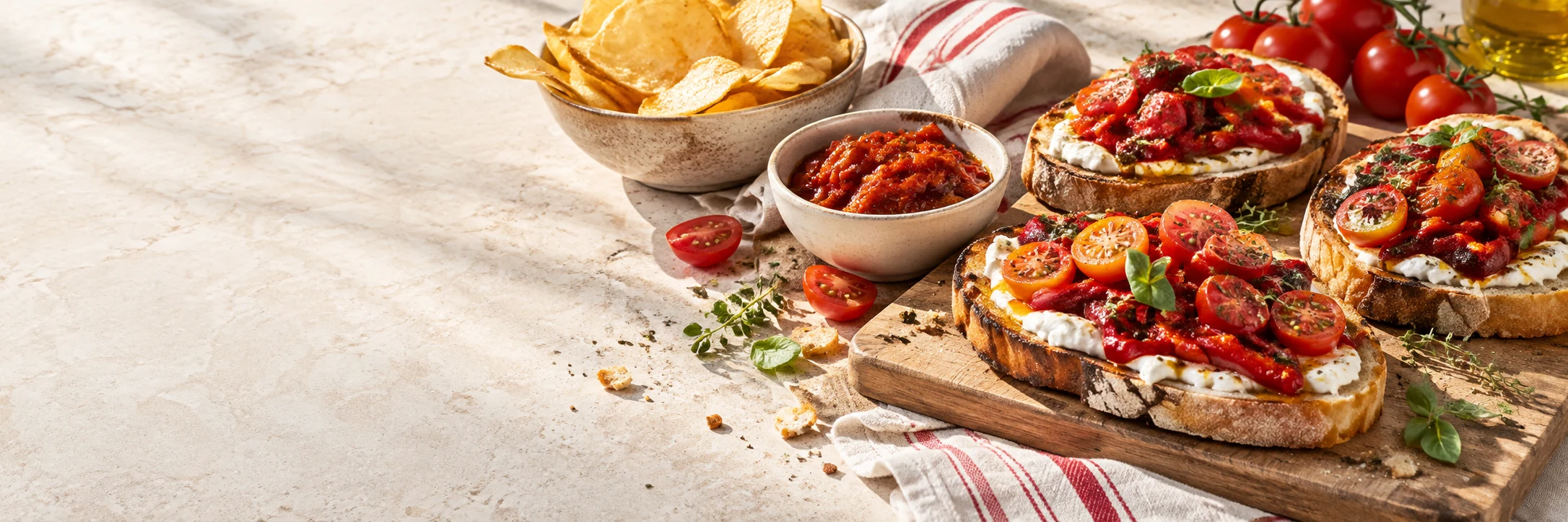 Sonniger Genussmoment mit knusprigem Brot, cremigen Aufstrichen und Tomaten